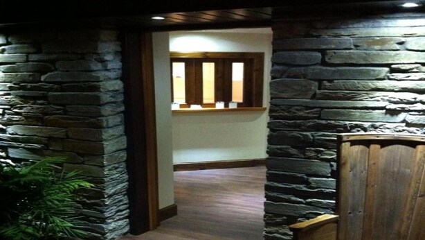 A hallway with stone walls, wooden door, and a bench. - Smithfield guesthouse (Dounby)