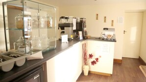 A hotel reception area with a glass display case, a coffee machine, and a vase with flowers. - Smithfield guesthouse (Dounby)