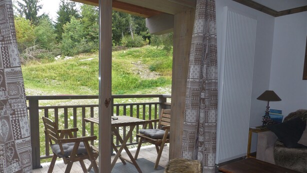 A room with a sliding glass door leading to an outdoor deck with a table and chairs.