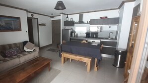 A compact living space with a sofa, a dining table, and a kitchenette.