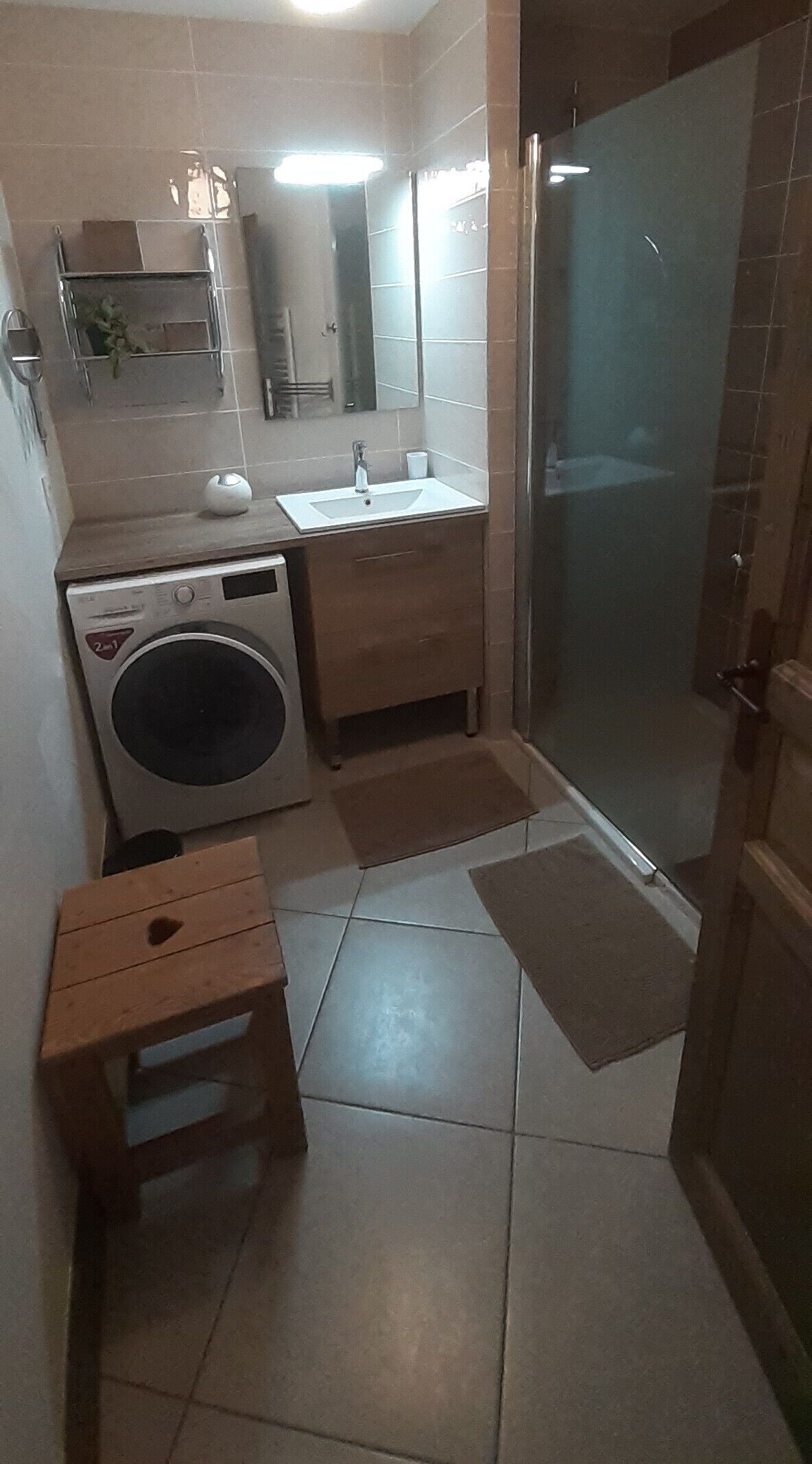 Ein kleines Badezimmer mit Waschmaschine, Waschbecken und Dusche.