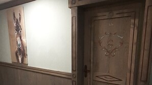 A hallway with a wooden door, a wall-mounted artwork, and a patterned floor.