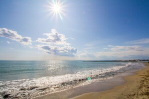 A beach with clear skies and sunlight reflecting off the water.