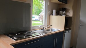 Cocina compacta con estufa integrada, un lavamanos y ventana con vistas al exterior.