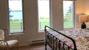 Ein Schlafzimmer mit einem Bett, einem Sessel und drei Fenstern.