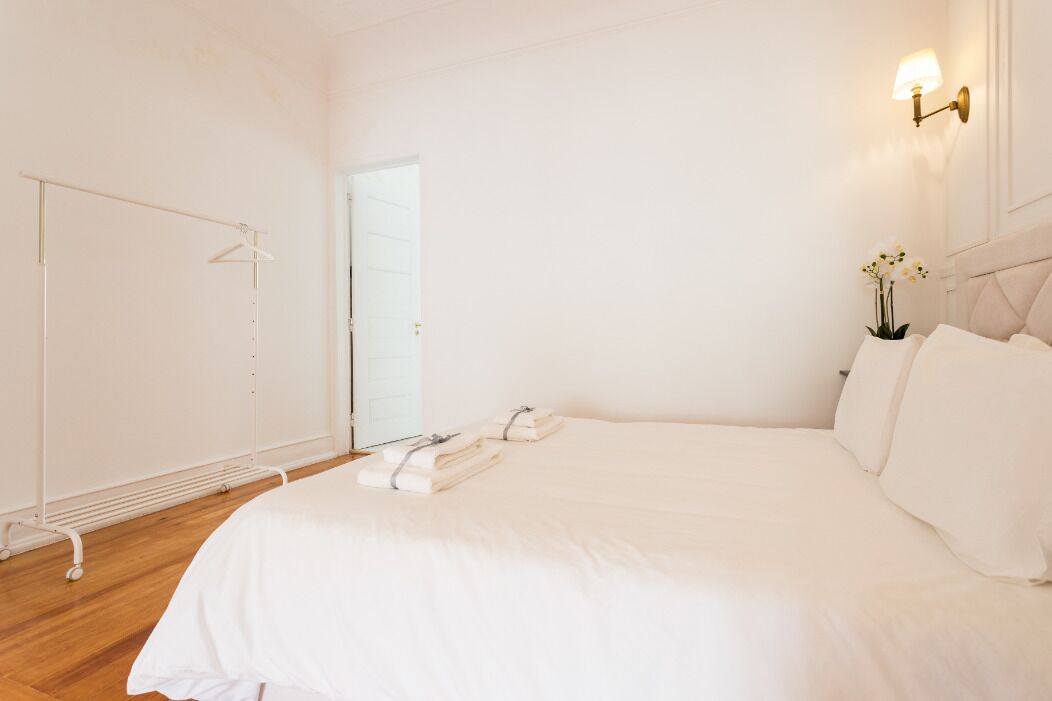 A minimalist bedroom with a large bed, a wardrobe, and a wall-mounted light fixture.
