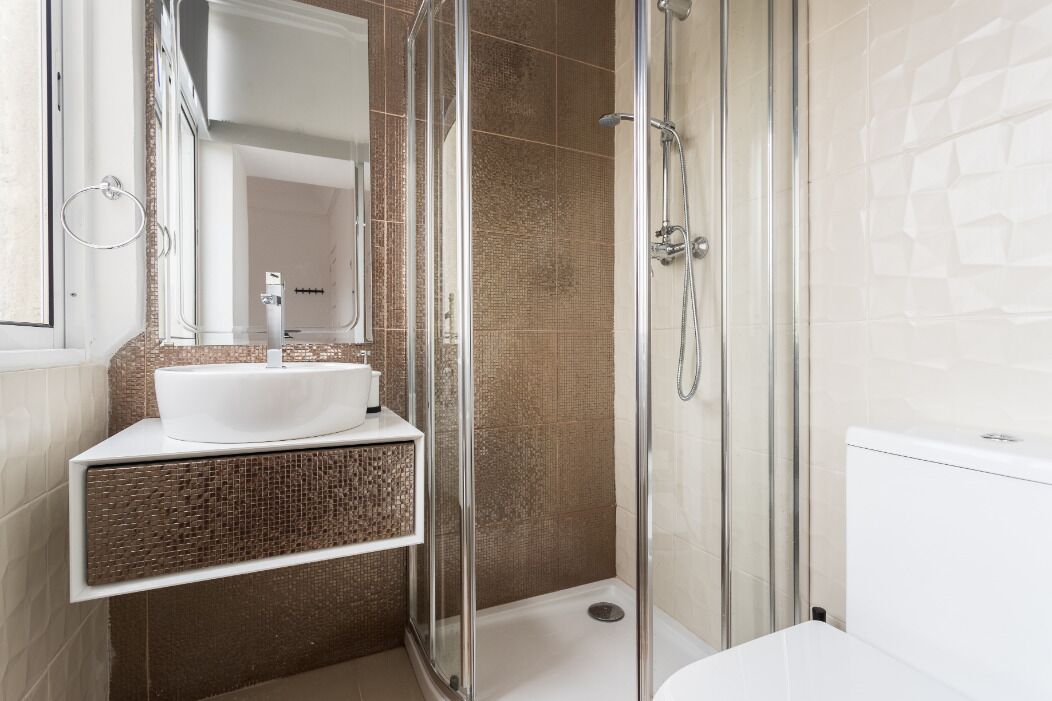 A modern bathroom with a glass-enclosed shower, a white sink, and a white bathtub.