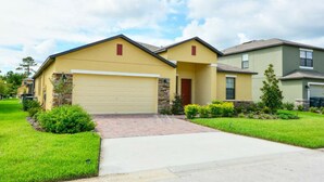 A two-story residential house with a yellow facade, a stone accent wall, and a red door. - Private Pool - Cozy Vacation Home  Near Disney! (Davenport)