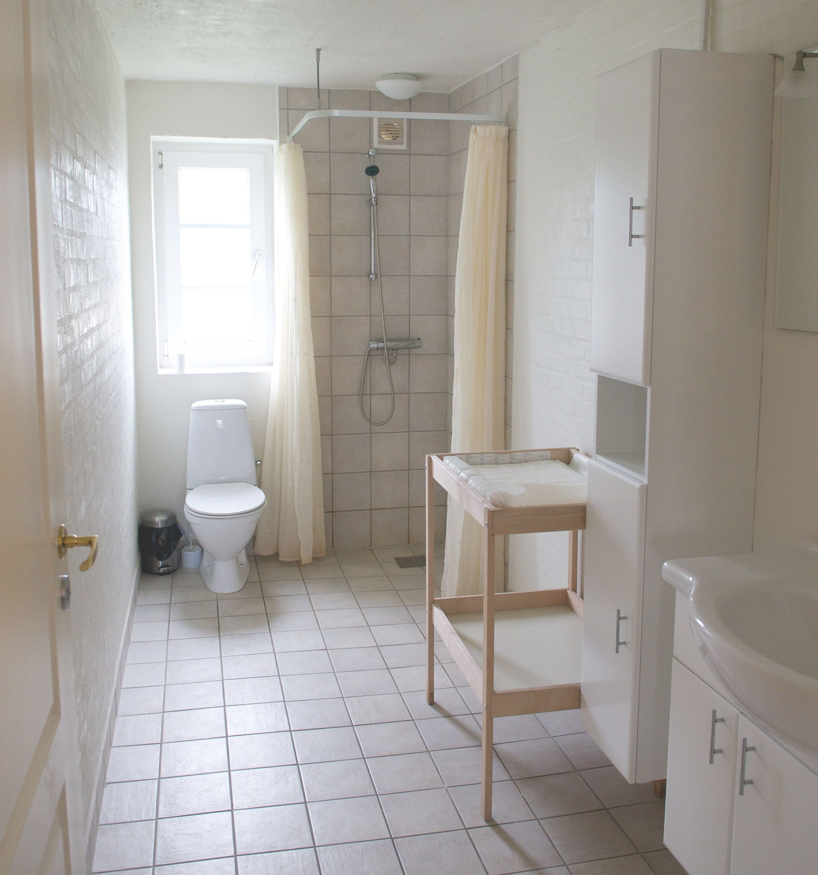 A bathroom with a toilet, shower, and a small wooden table.