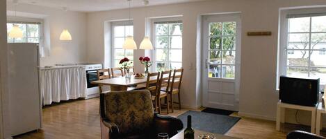 A dining area with a table set for two, a sofa, and a television on a stand.
