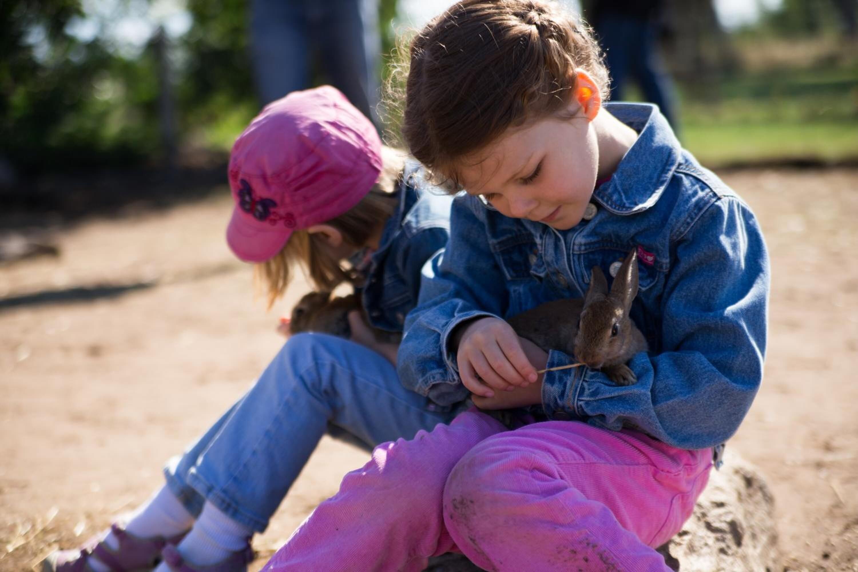 Twee kinderen zitten op een zandig oppervlak buiten.