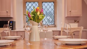 A dining table set with white plates, wine glasses, and a pitcher of flowers. - The Hunting Tower Chatsworth Estate (Chatsworth)