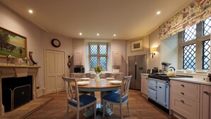 A kitchen with a dining table, chairs, a refrigerator, and a stove. - The Hunting Tower Chatsworth Estate (Chatsworth)