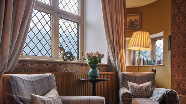 A cozy room with two plaid armchairs, a small table with a vase of flowers, and a lamp. - The Hunting Tower Chatsworth Estate (Chatsworth)