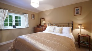 Un dormitorio con una cama grande, un aparador, una mesita de noche, una ventana con cortinas y un cuadro en la pared.