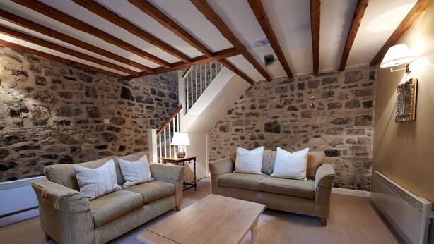 Una sala de estar acogedora con dos sofás, una mesa de centro de madera y una pared de piedra.