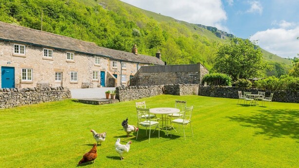 A stone building with a blue door, a grassy lawn, and a stone wall. - Heron Cottage, Upperdale | Peak District (Buxton)