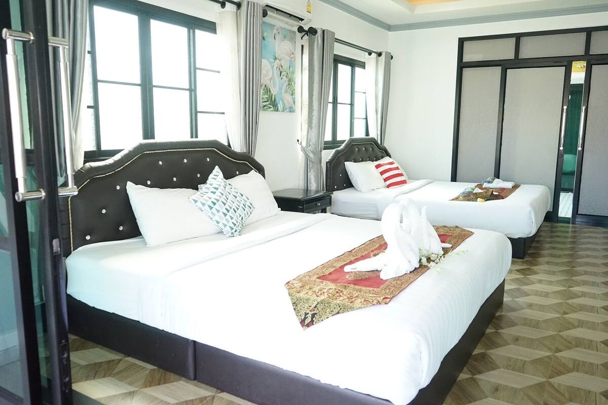 A hotel room with two beds, each with a headboard, white bedding, and a decorative pillow.