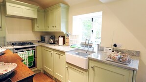 A kitchen with light green cabinets, a sink, a stove, and a window providing natural light.