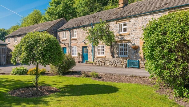 A row of stone houses with a well-maintained lawn and trees. - Riversdale Farm Cottage, Upperdale | Peak District (Buxton)