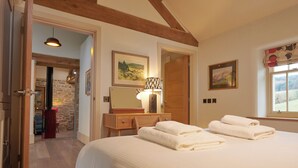 Camera da letto con soffitto in legno, letto con lenzuola bianche, lampada da comodino e finestra con vista.