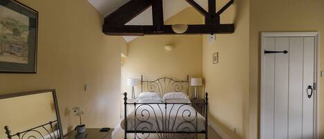 A bedroom with a bed, bedside lamps, a dresser, a mirror, and a door.