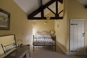 A bedroom with a bed, bedside lamps, a dresser, a mirror, and a door.