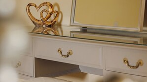 Une coiffeuse avec un miroir, une décoration en forme de cœur et un tableau encadré accroché au mur.