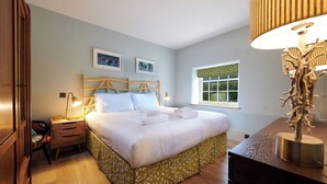 A neatly arranged bedroom with a bed, bedside tables, a lamp, and a window with a view. - Rye Croft Cottage on the Chatsworth Estate (Edensor)