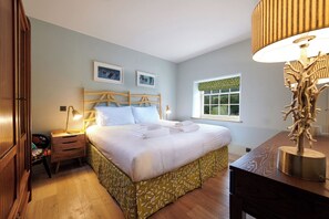 Relax in a spacious room with a large bed, wooden nightstand, and comfortable chair.
