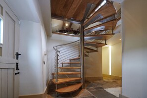 Stunning spiral staircase leads to a cozy living area with a sofa and table.