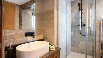 A modern bathroom with a large white sink, a glass-enclosed shower, and a wooden vanity.