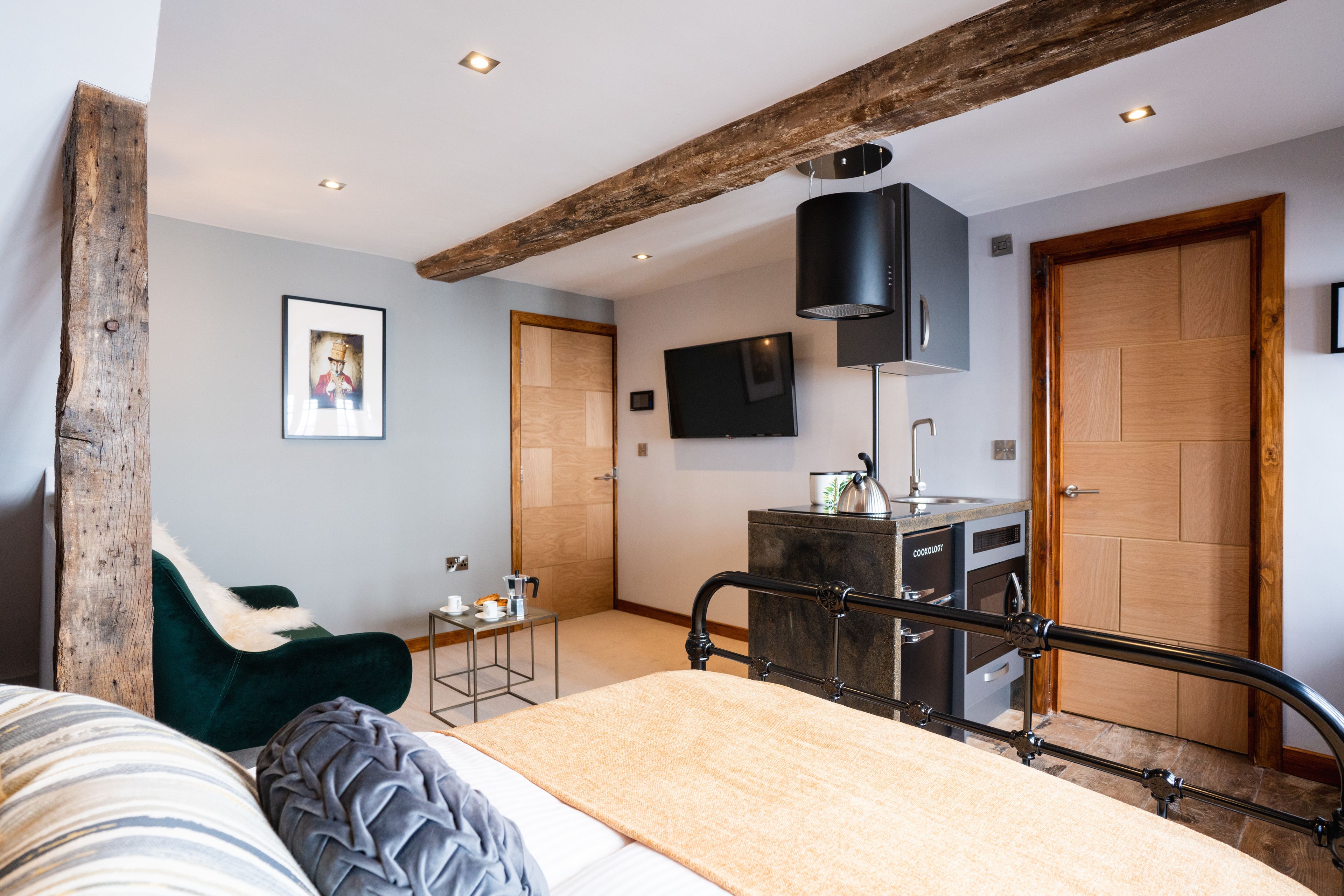 Un dormitorio moderno con una cama, un escritorio, una silla, un televisor y una puerta de madera.