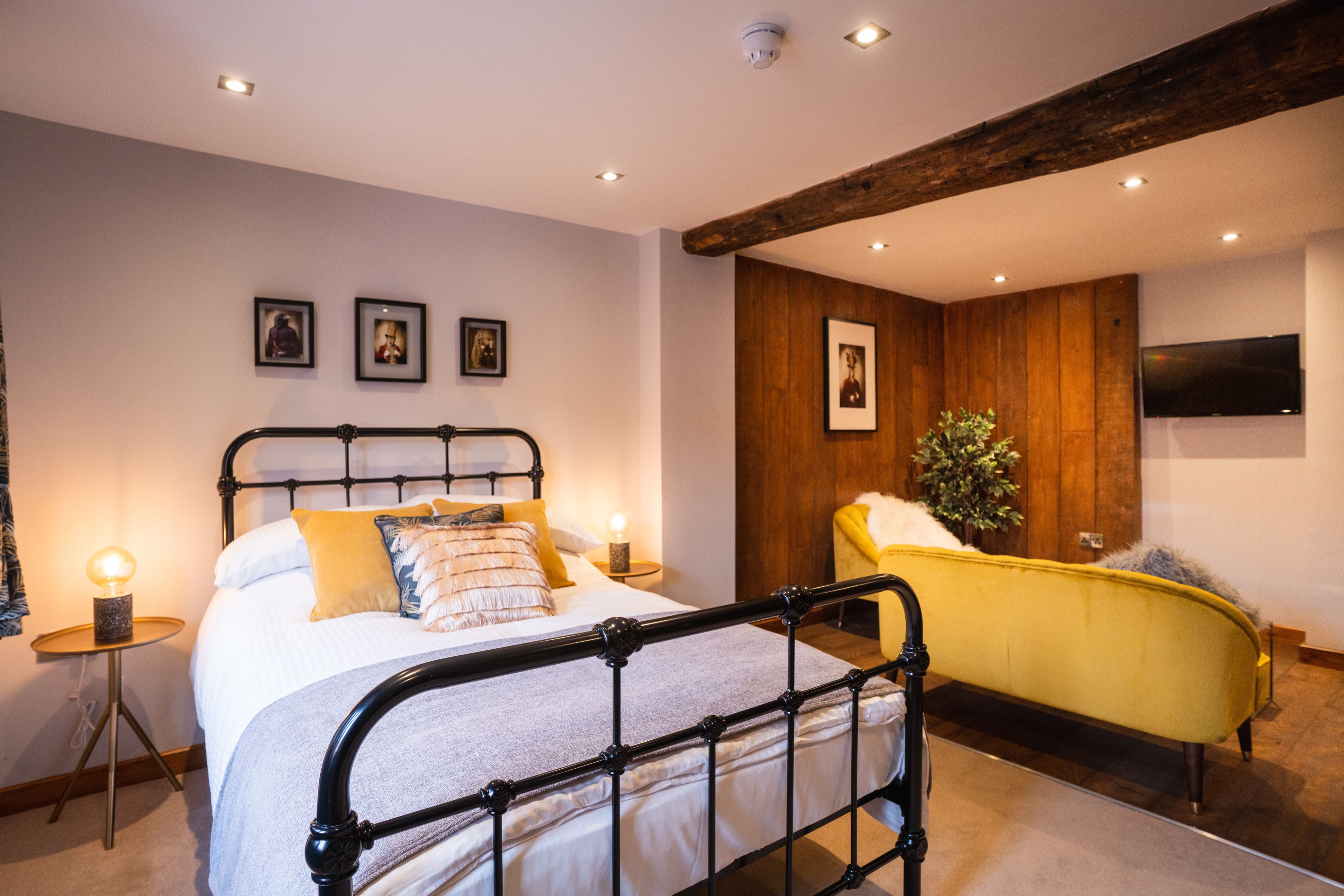 Une chambre à coucher comprenant un lit, des tables de chevet, un téléviseur et un panneau mural en bois.