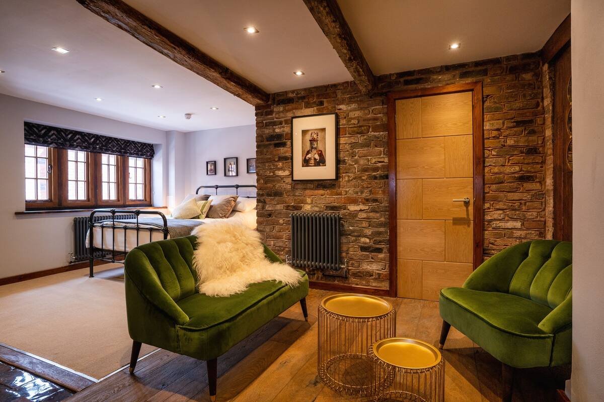 A cozy room with a green sofa, a small round table, and a stone wall.