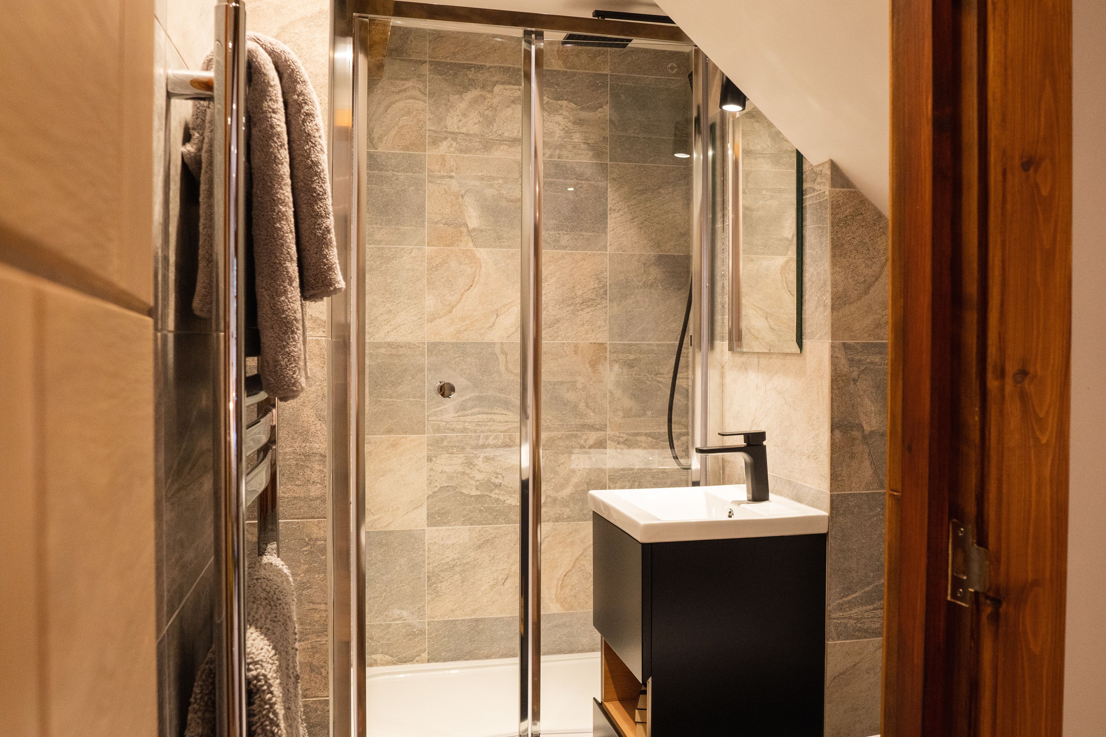 A modern bathroom with a glass shower enclosure, a built-in sink, and a towel rack.