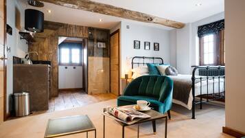 A cozy bedroom with a bed, a green armchair, a small table with a newspaper, and a radiator.
