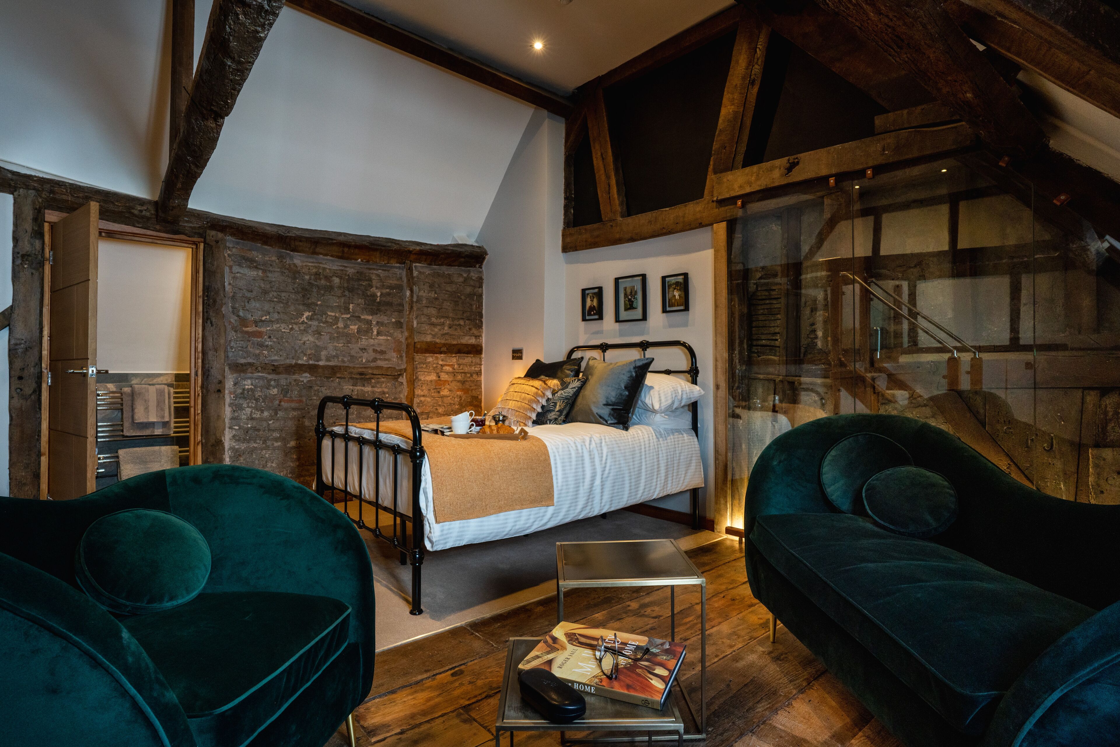 Een gezellig slaapkamer met een bed, een groene bank en een houten vloer.