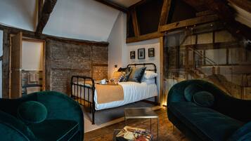 Een gezellig slaapkamer met een bed, een groene bank en een houten vloer.