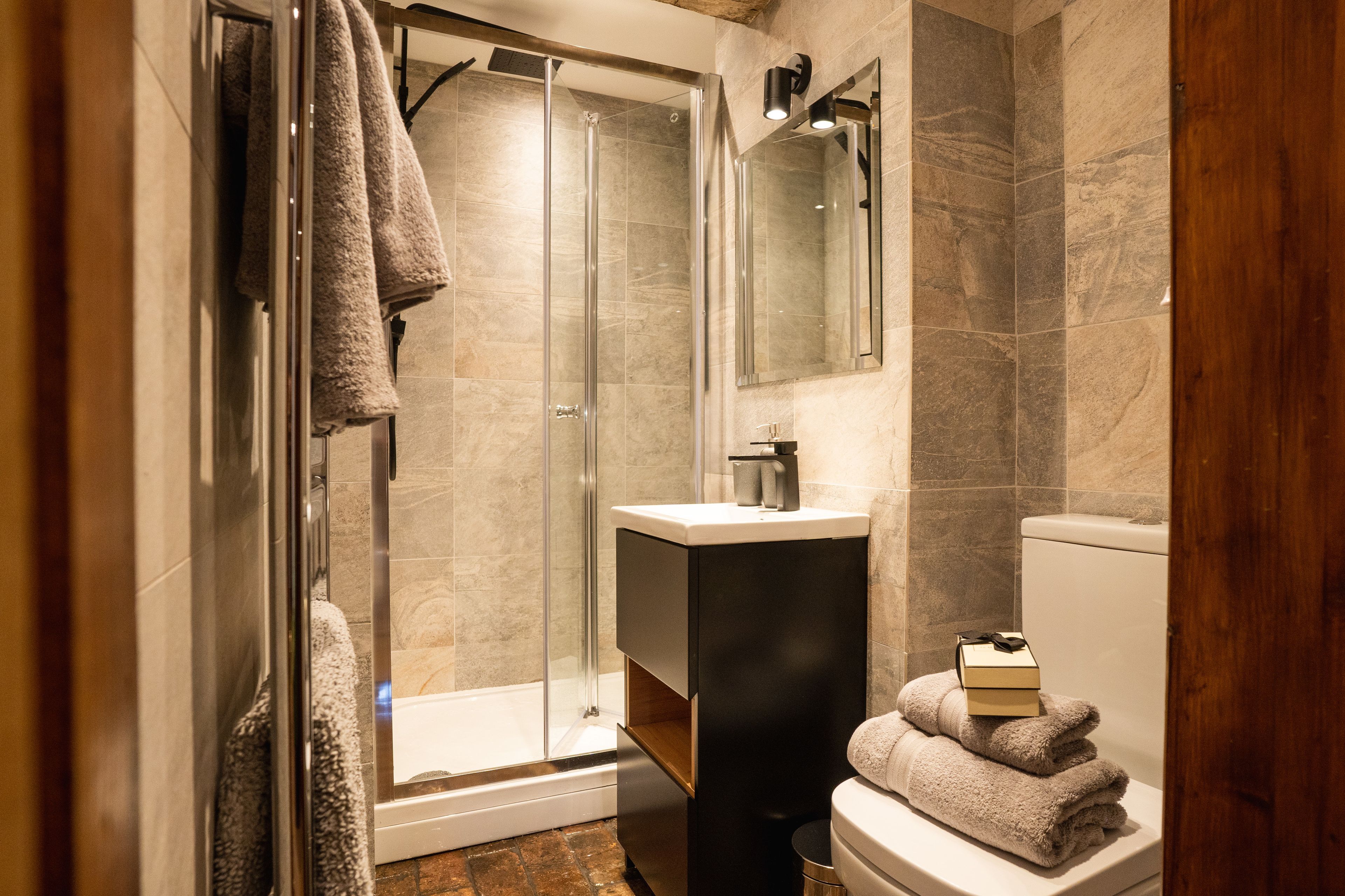 Un bagno moderno con box doccia in vetro, lavandino e servizi igienici.