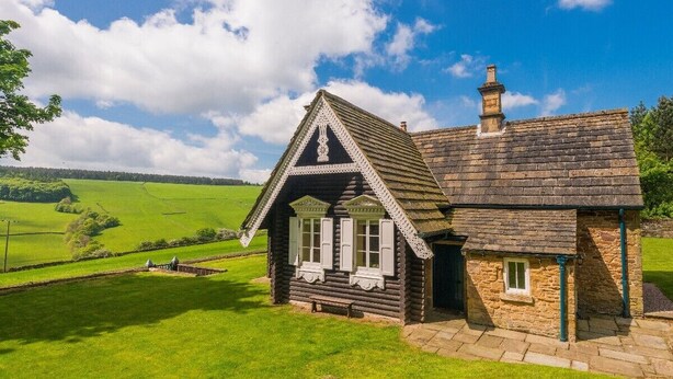 A traditional stone cottage with a pitched roof, a chimney, and a small porch with white shutters. - Russian Cottage Chatsworth Estate (Edensor)
