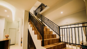A modern staircase with wooden steps and black railings, leading to a bedroom with a bed and a visible door number 103. - Nova Guest House (Pererenan)