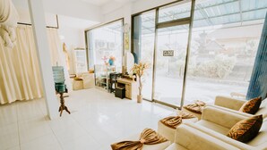 A spacious room with a large window, a sofa set, a small table, and a water dispenser. - Nova Guest House (Pererenan)
