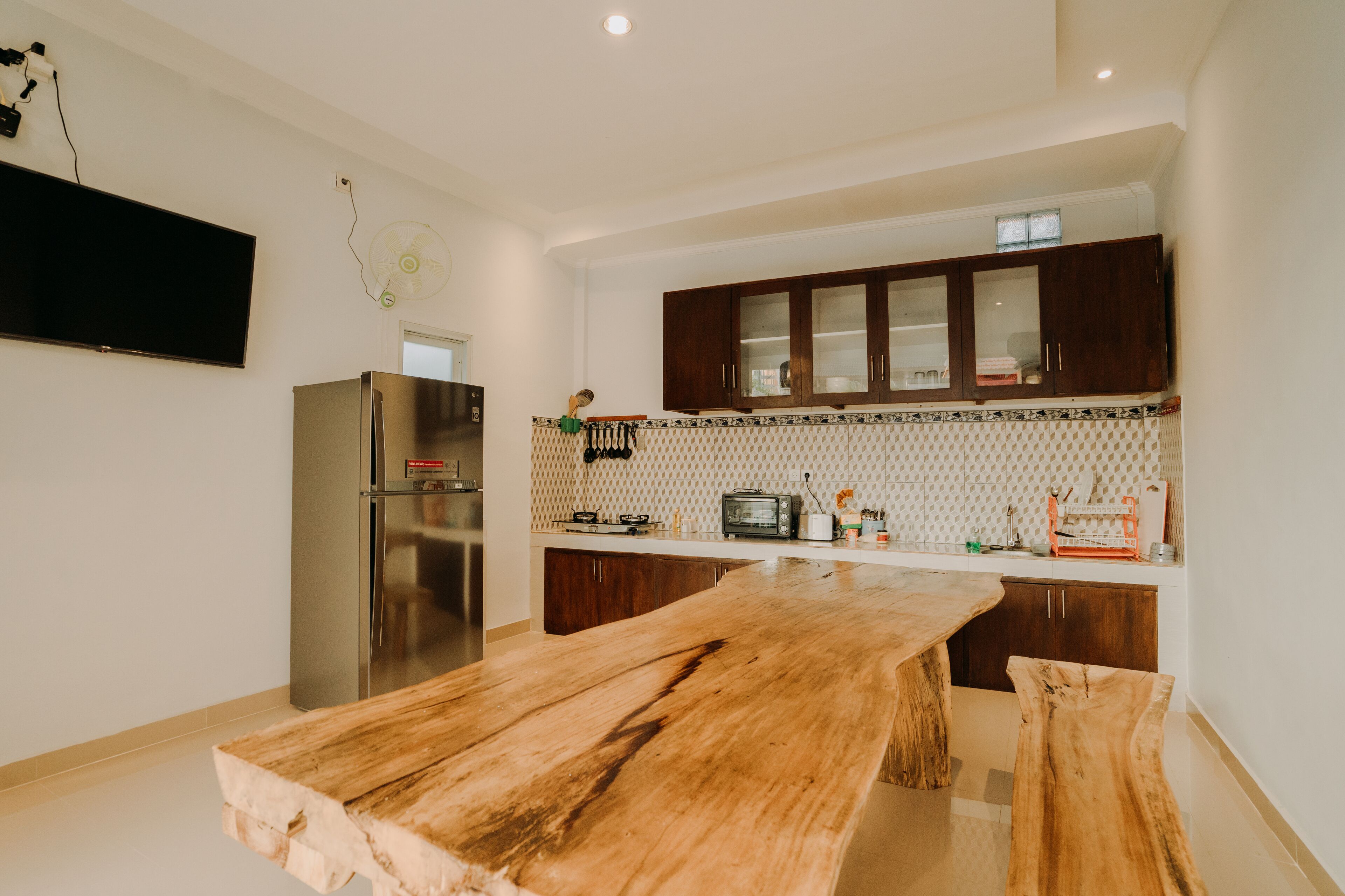 A modern kitchen with a wooden table, stainless steel appliances, and dark wooden cabinets.