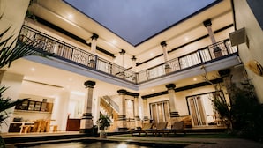 A multi-level outdoor living area with a pool, seating, and a staircase. - Nova Guest House (Pererenan)