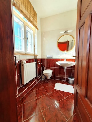Une salle de bain avec des toilettes, un lavabo et une fenêtre.