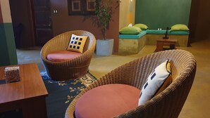 A room with wicker chairs, a small table, a plant, and a green wall. - My Village (Thissamaharama)