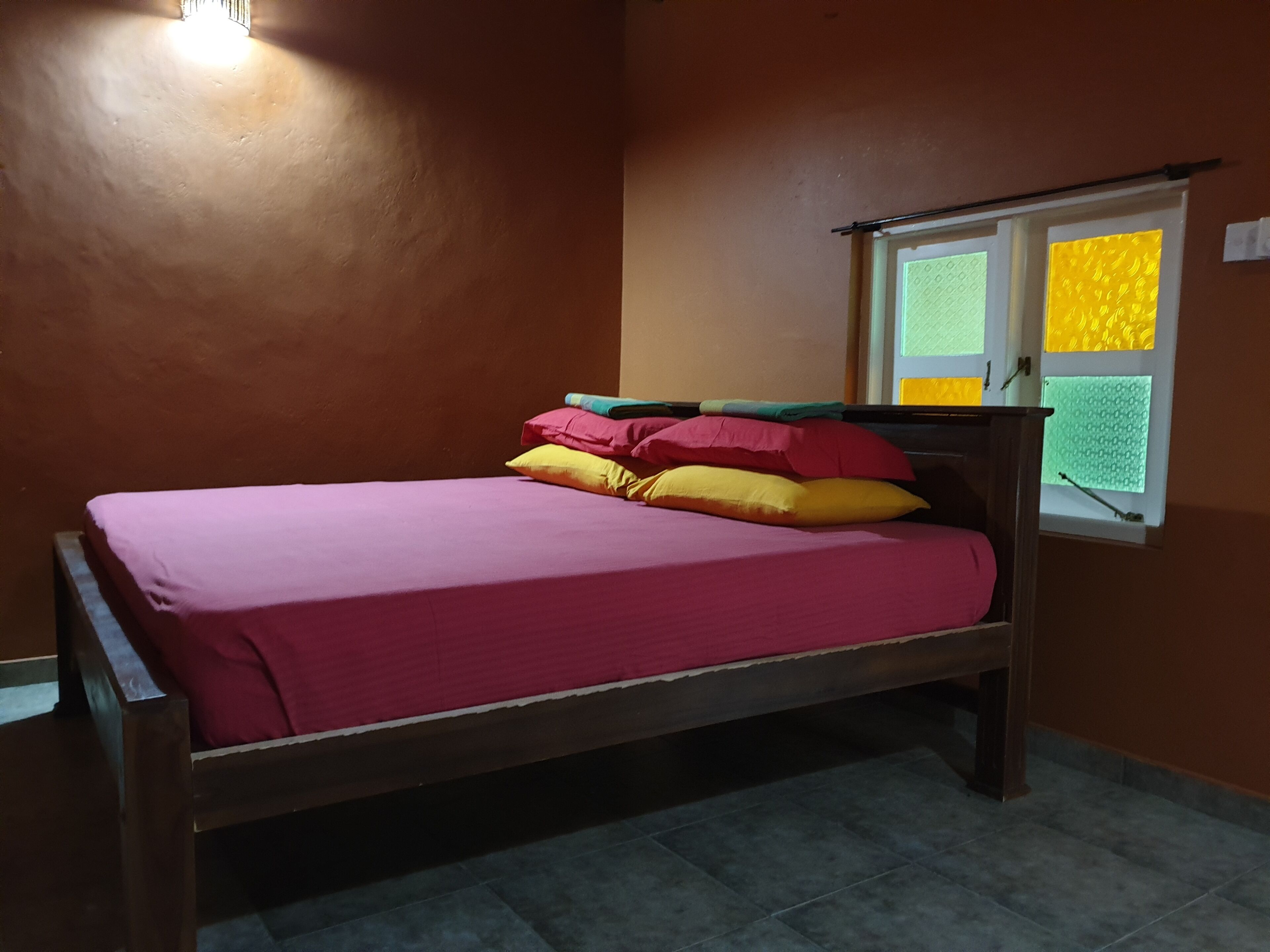 A single bed with a wooden frame and a red mattress.
