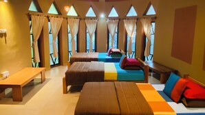 A room with two beds, a bench, and a ceiling fan. - My Village (Thissamaharama)