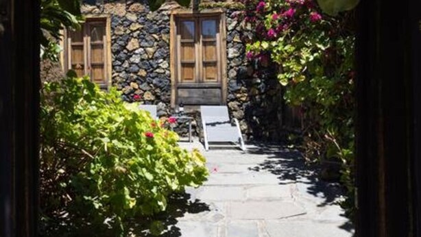 Uma trilha de pedra leva a um edifício rústico com portas de madeira e uma parede de pedra.